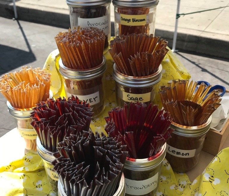 Jars of flavored honey sticks at a market stall